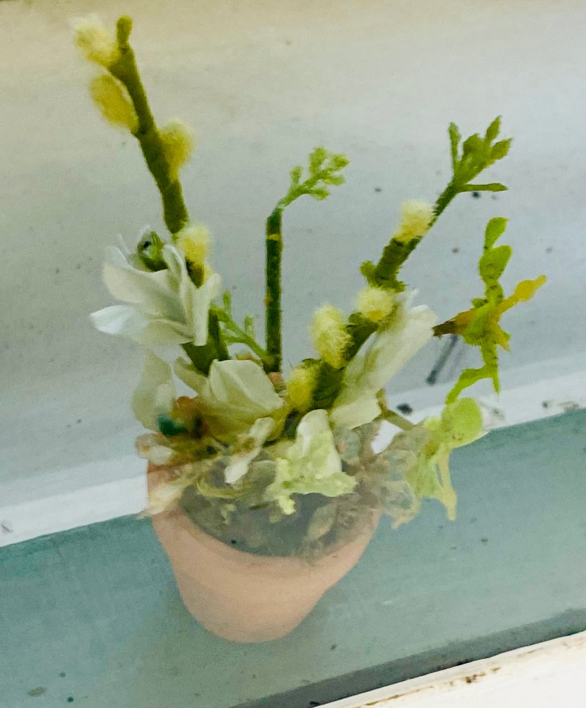 An arrangement of pale off-white and green buds in a clay flower pot. In real life, it is 4" high.